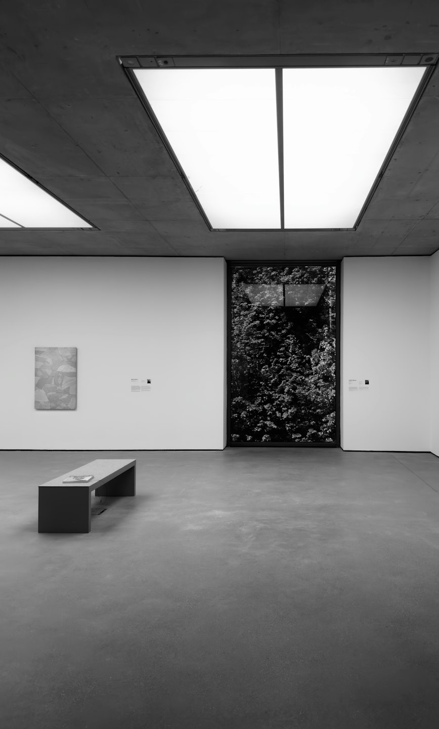 Modern art gallery with abstract painting and book on bench.