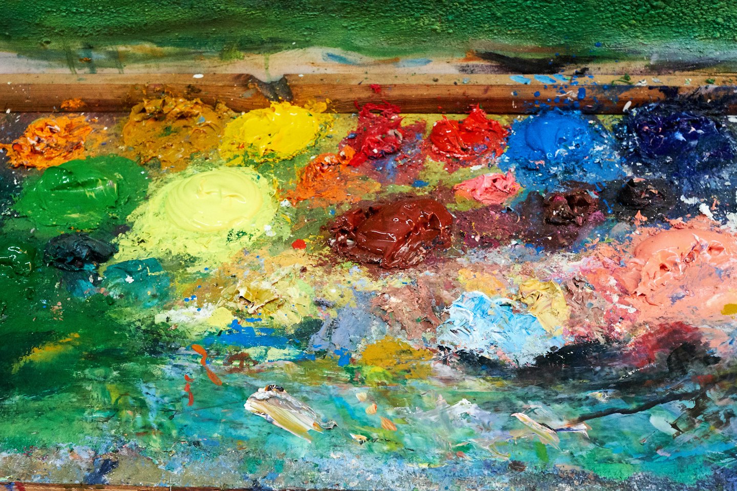 Artist's wooden palette with swirls of mixed oil paints.