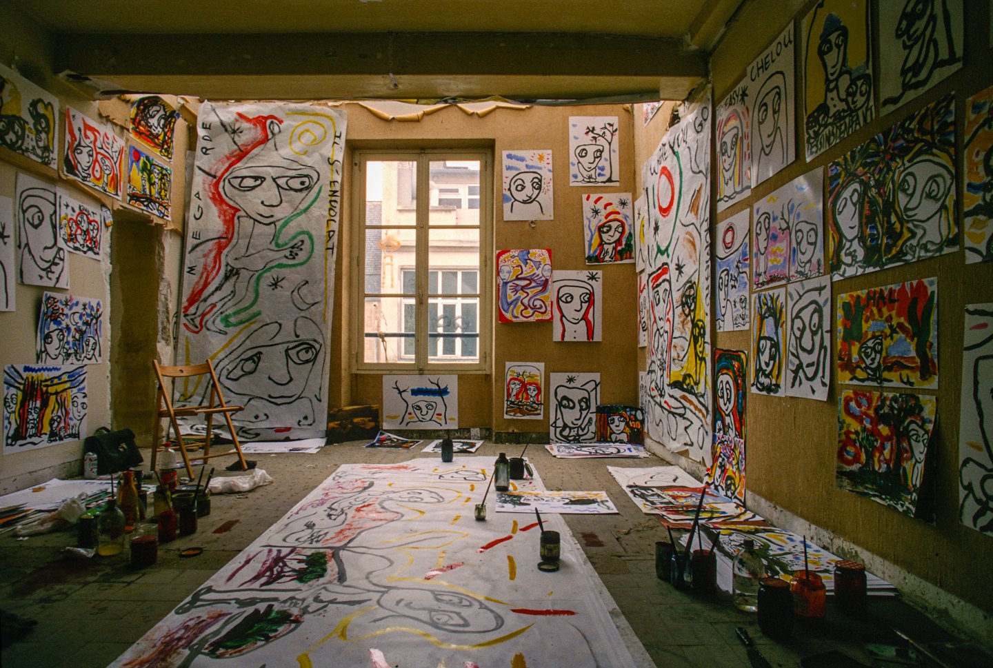 Artist's studio filled with abstract paintings and art supplies.