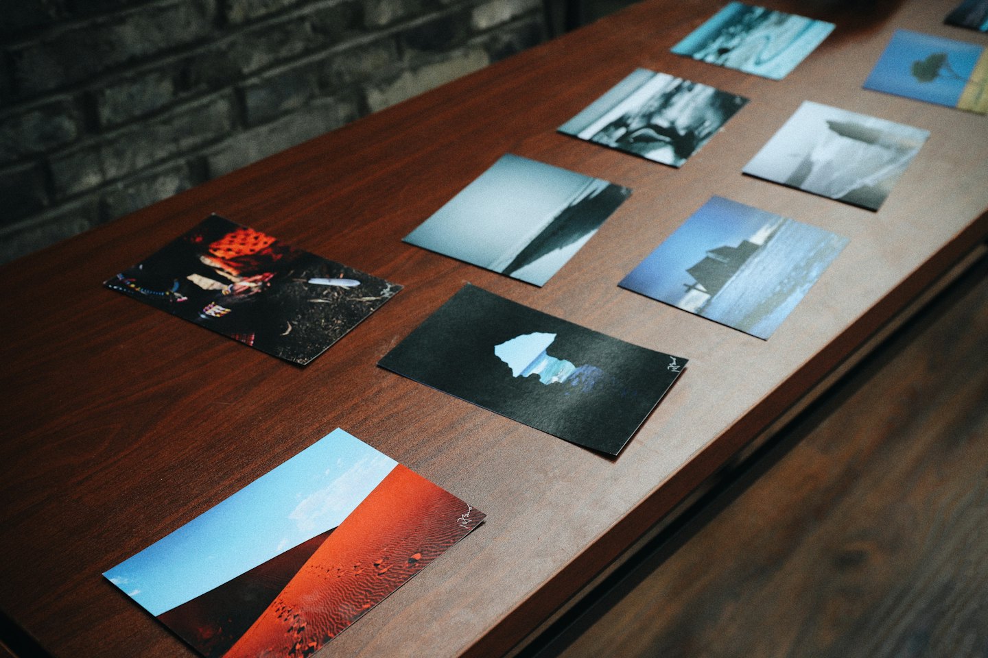 Various art prints arranged on a polished wooden table.